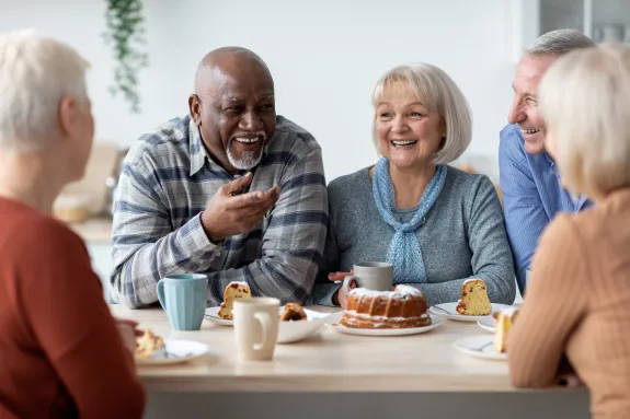 International group of positive elderly people drinking tea with cake